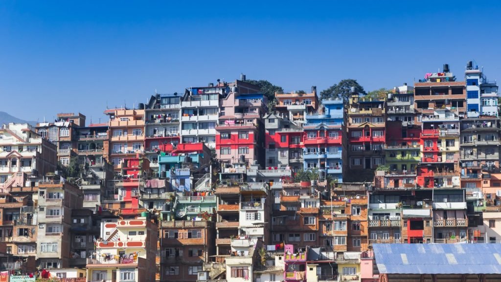 Multi-colored buildings stacked on the hills of Kirtipur City with a clear blue sky