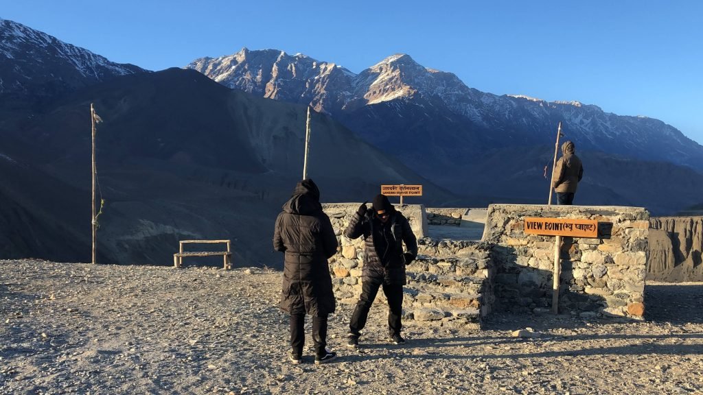 Visitors at a viewpoint in Muktinath with majestic mountains in the backdrop.