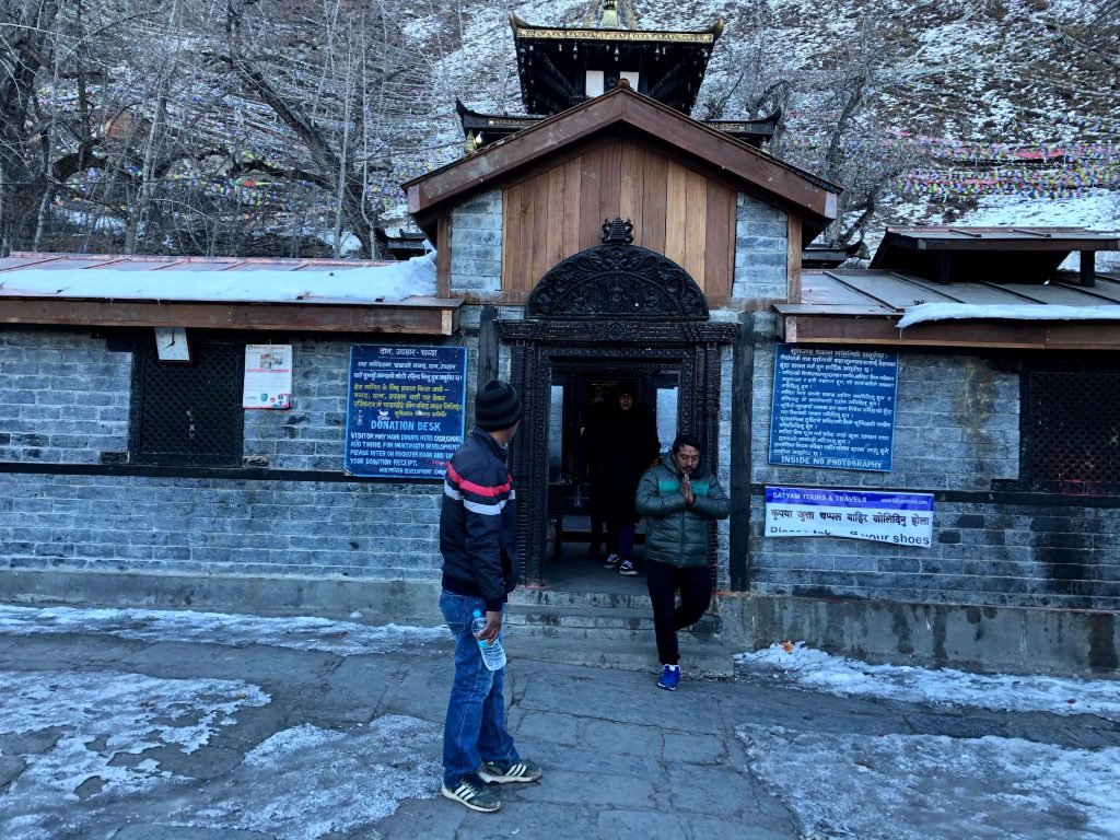 Devotees outside the Muktinath Temple in a snowy setting.