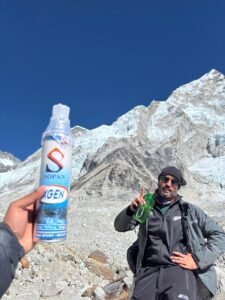 Person holding oxygen canister used for acute mountain sickness with mountains in background.