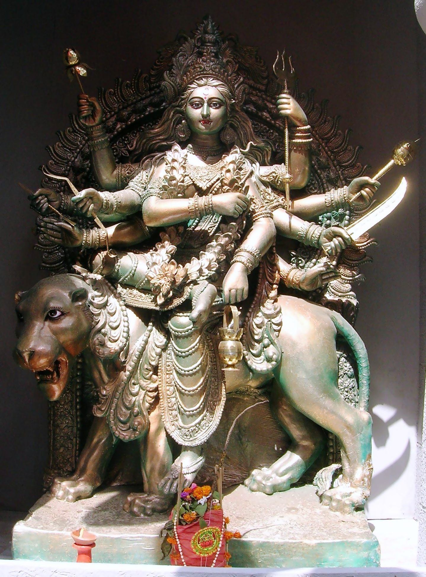Bronze idol of Goddess Chandraghanta riding a lion, with ten arms holding weapons and symbolic items.