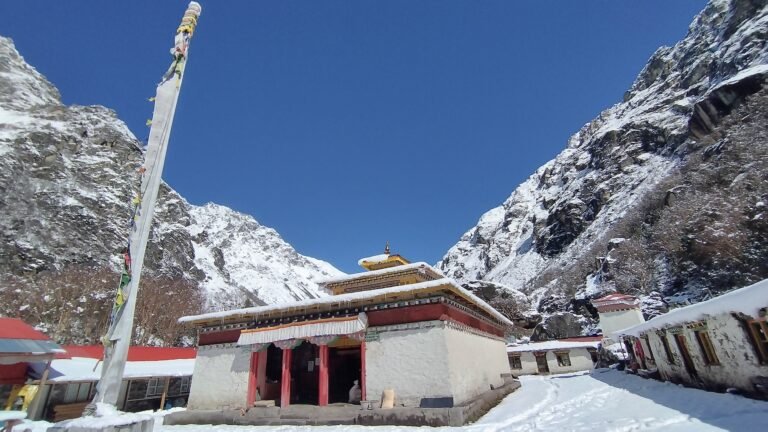 Snow-covered Lapchi Gumba monastery with colorful prayer flags in Nepal Himalayas