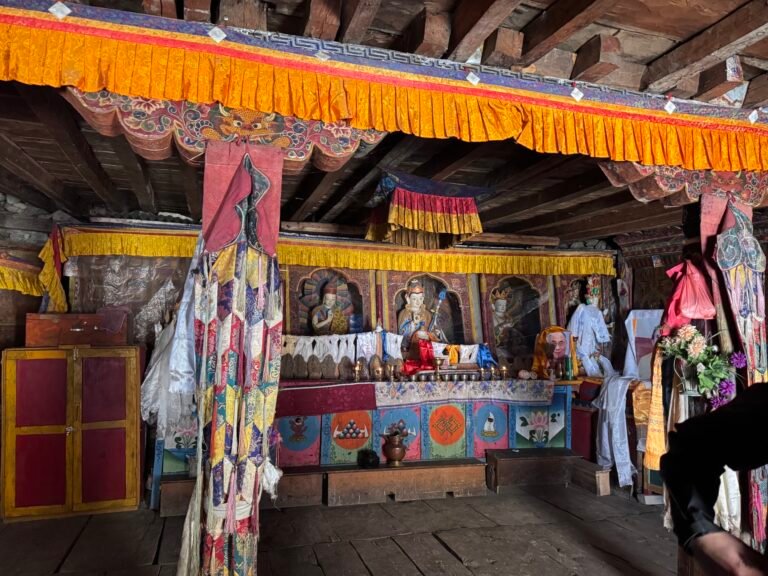 Interior of Pungyen Gumba shrine on the Manaslu Circuit Trek, featuring colorful Buddhist statues, tapestries and ritual offerings