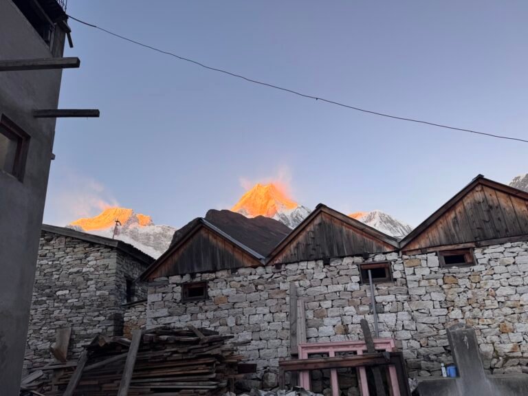 Sunrise alpenglow on Mount Manaslu behind stone houses in Samagaun village