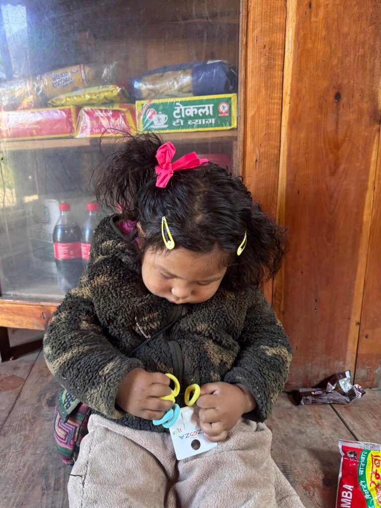 Local Nepali girl playing with colorful rings inside a rustic tea house on the Manaslu Circuit Trek.