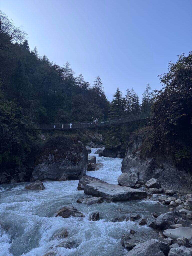 Suspension bridge over a mountain river with a hiker in forest on the Manaslu Circuit Trek, Nepal