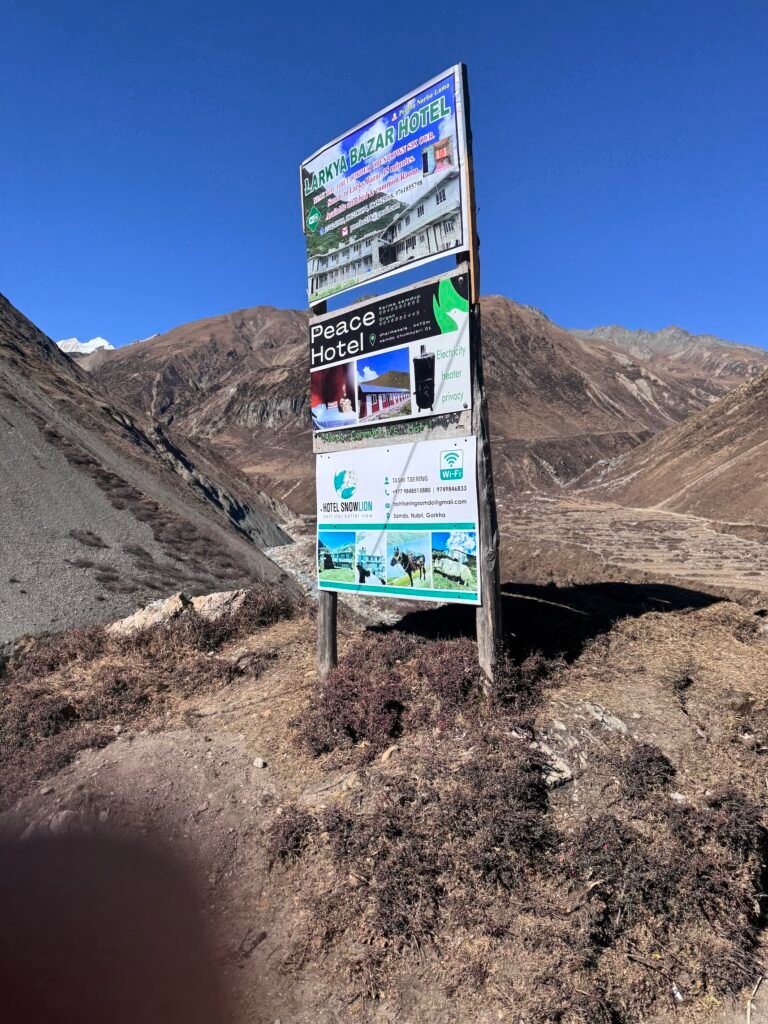 Hotel signboard at Samdo village on the Manaslu Circuit Trek with Himalayan peaks in the background