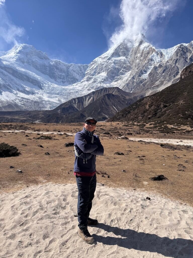 Guide Sagar in alpine meadow before snow-capped peaks at Pungin Gumba on the Manaslu Circuit Trek