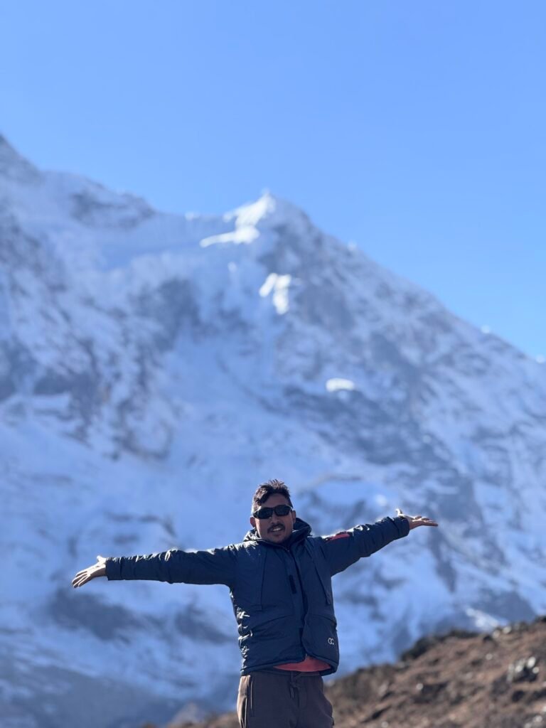 Hiker with arms outstretched at Pungin Gumba viewpoint overlooking snow-covered Manaslu peaks